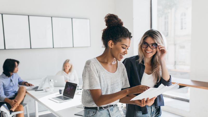 Zwei Frauen im Vordergrund stehend - zwei Frauen im Hintergrund sitzend
