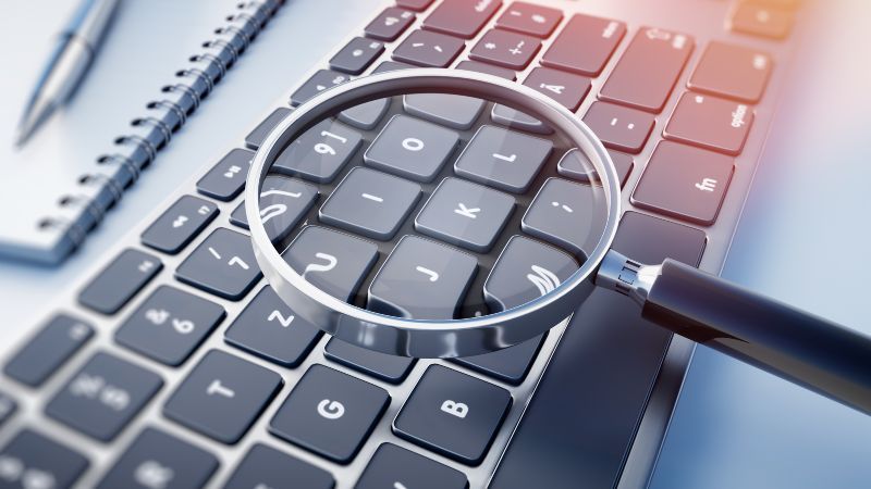 Lupe vergrößert Buchstaben einer Computer-Tastatur