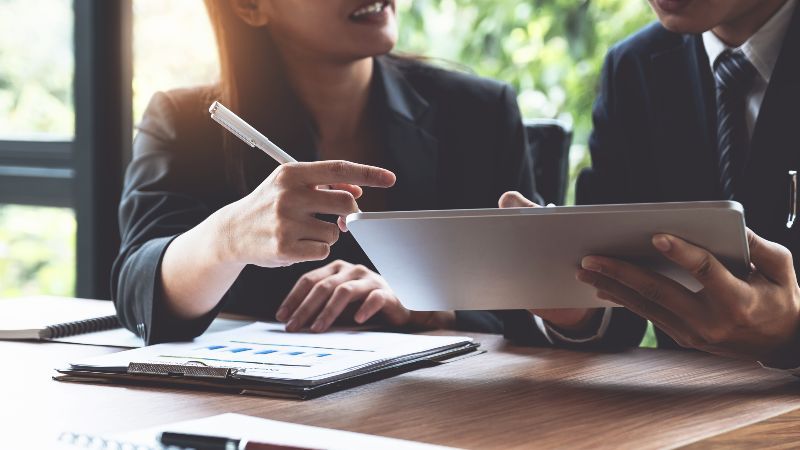 Frau mit Schreibstift und Mann mit Tabletcomputer im Gespräch