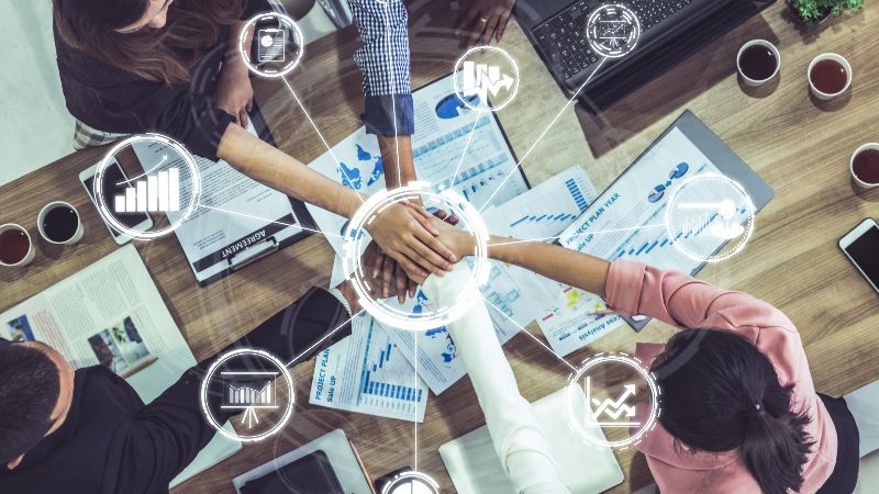 Hände besiegeln Zusammenarbeit mit 9 eingeblendeten Symbolen und einem Kreis in der Mitte