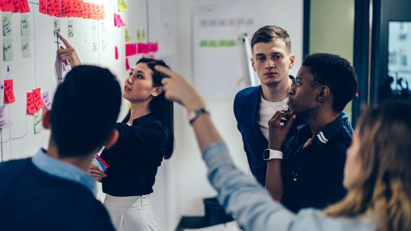 Fünf Personen vor Wand mit Post-its