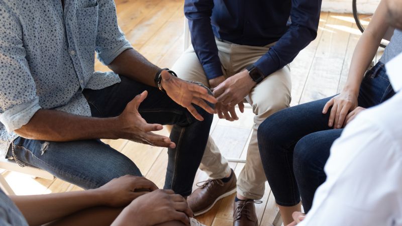 Bildauschnitt der Hände einer sitzenden Personengruppe