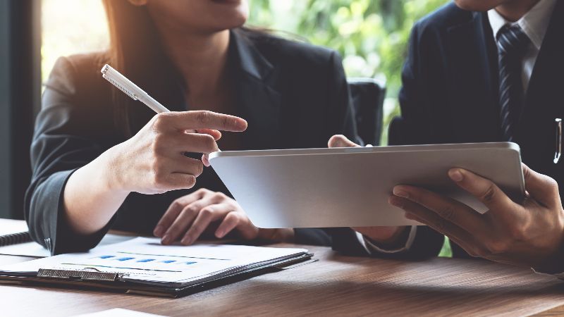 Frau mit Schreibstift und Mann mit Tabletcomputer im Gespräch
