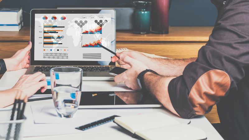 Zwei sitzende Personen sehen Diagramme auf einem Bildschirm