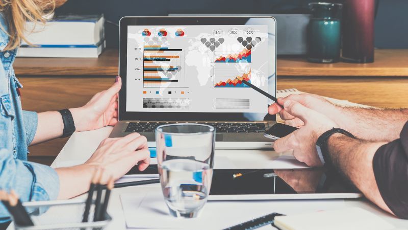 Zwei sitzende Personen sehen Diagramme auf einem Bildschirm