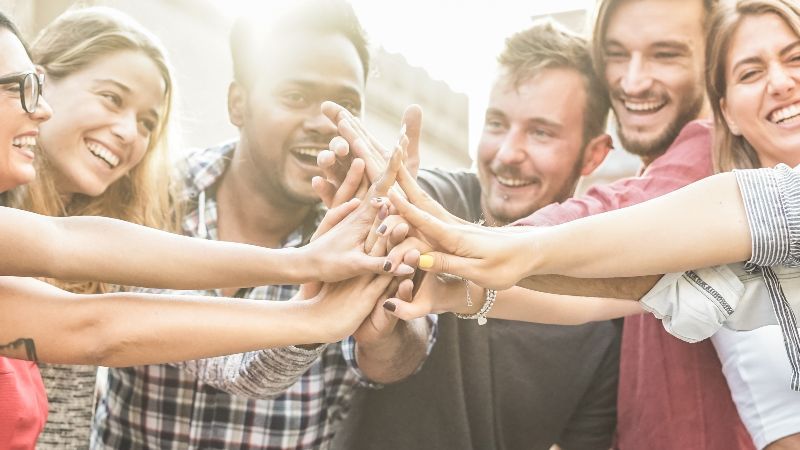 Fröhliche Menschen führen Hände zusammen