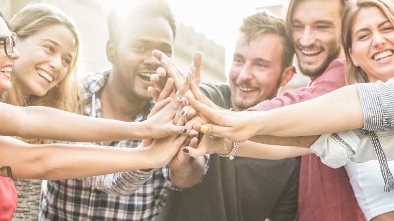 Fröhliche Menschen führen Hände zusammen